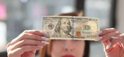 Bir kişi yüz doların gerçek olup olmadığını kontrol ediyor