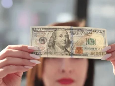 Bir kişi yüz doların gerçek olup olmadığını kontrol ediyor